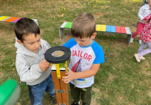 chłopcy poznają lupę na terenie ogródka "Słoneczna Akademia"